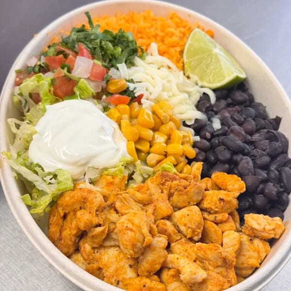 A colorful HP Taco Shop burrito bowl with chicken, rice, beans, corn, pico de gallo, cheese, sour cream, and lime.