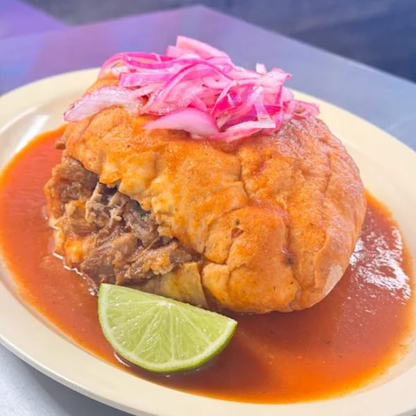 HP Taco Shop's torta ahogada, a Mexican sandwich, with pickled red onions and a lime wedge.
